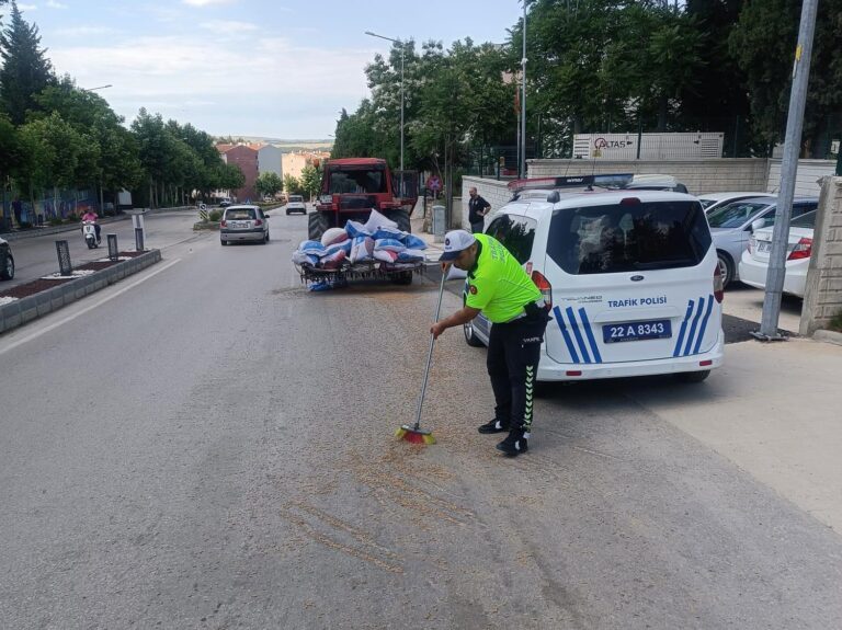 Polis, traktörden düşerek yola saçılan kuzu yemlerini topladı